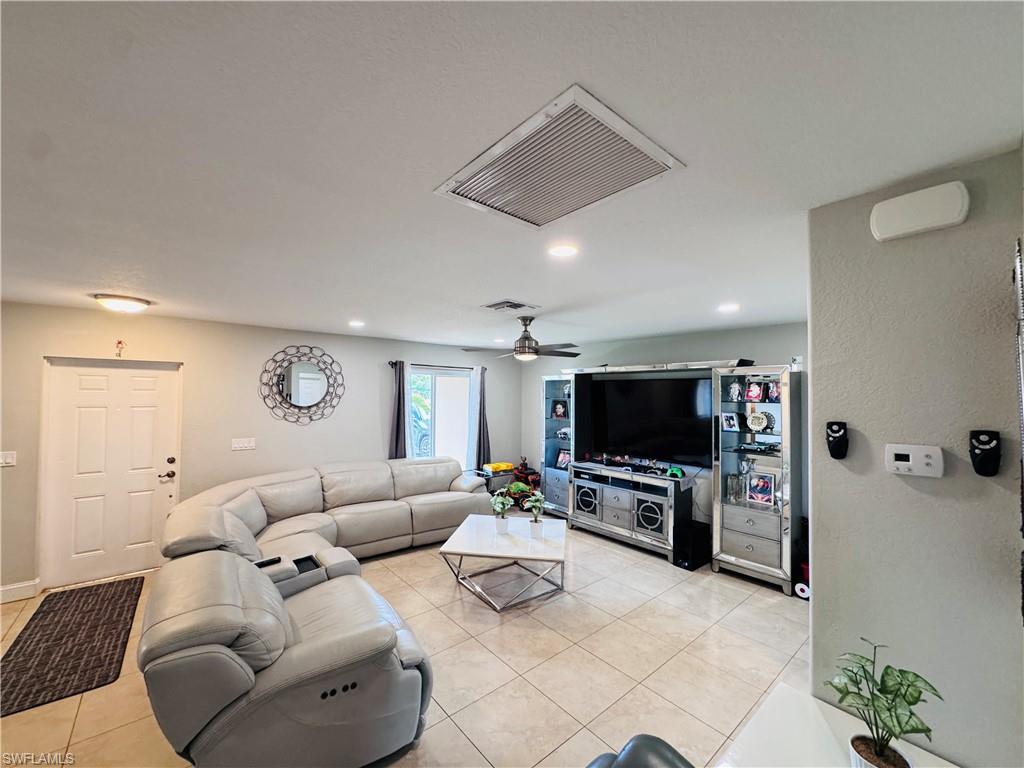 Living room with light tile patterned flooring, recessed lighting, and a textured wall