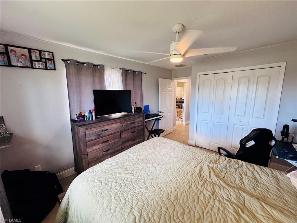 Bedroom featuring a ceiling fan, a closet, and light tile patterned floors
