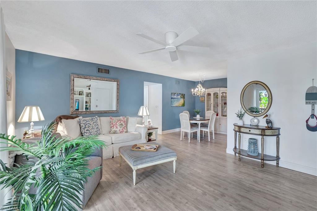 Living room with a textured ceiling, hardwood / wood-style flooring, and ceiling fan with notable chandelier