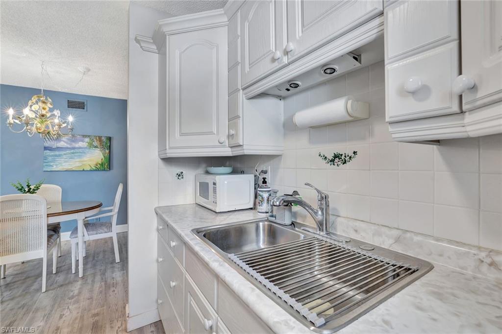 Kitchen featuring a textured ceiling, a notable chandelier, sink, white cabinets, and light hardwood / wood-style flooring
