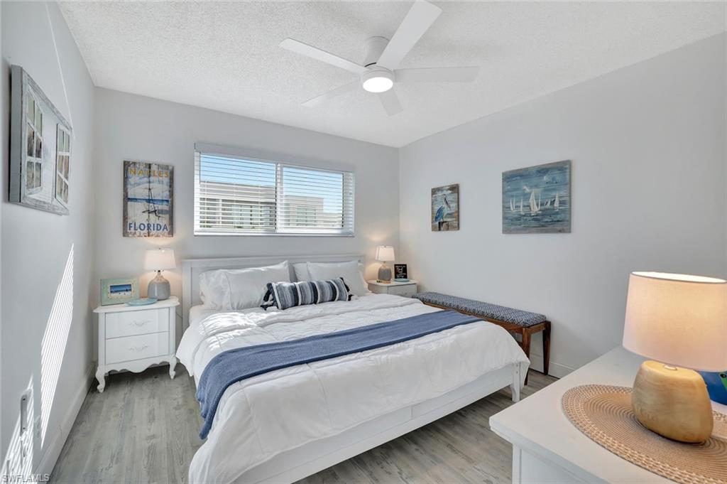 Bedroom with light hardwood / wood-style floors, a textured ceiling, and ceiling fan