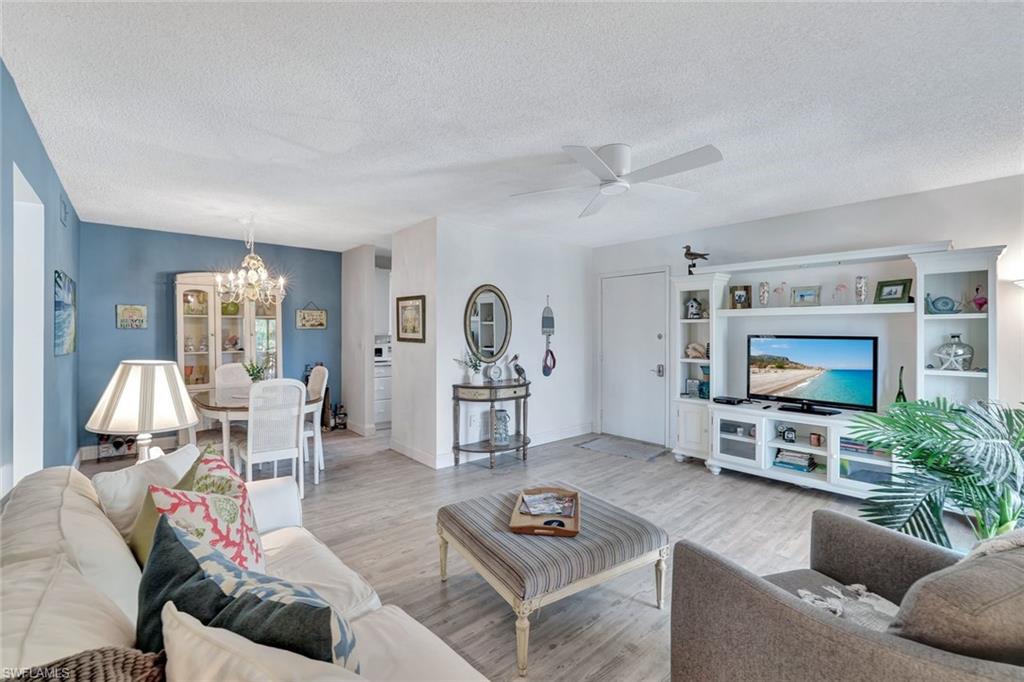 Living room featuring ceiling fan with notable chandelier, a textured ceiling, and light wood-type flooring