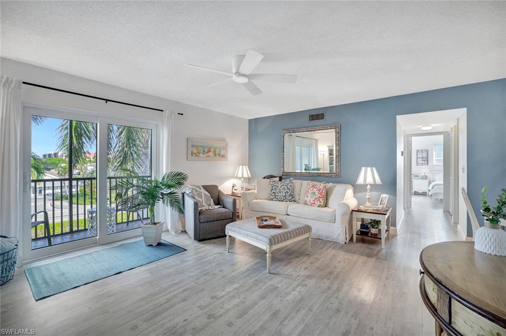 Living room featuring a textured ceiling, ceiling fan, and light hardwood / wood-style flooring