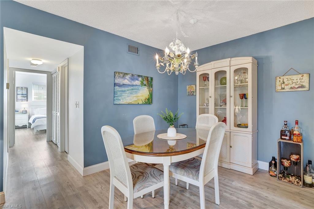 Dining room featuring light hardwood / wood-style flooring, a notable chandelier, and a textured ceiling