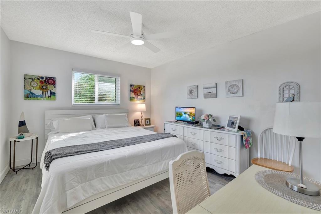 Bedroom with light wood-type flooring, a textured ceiling, and ceiling fan