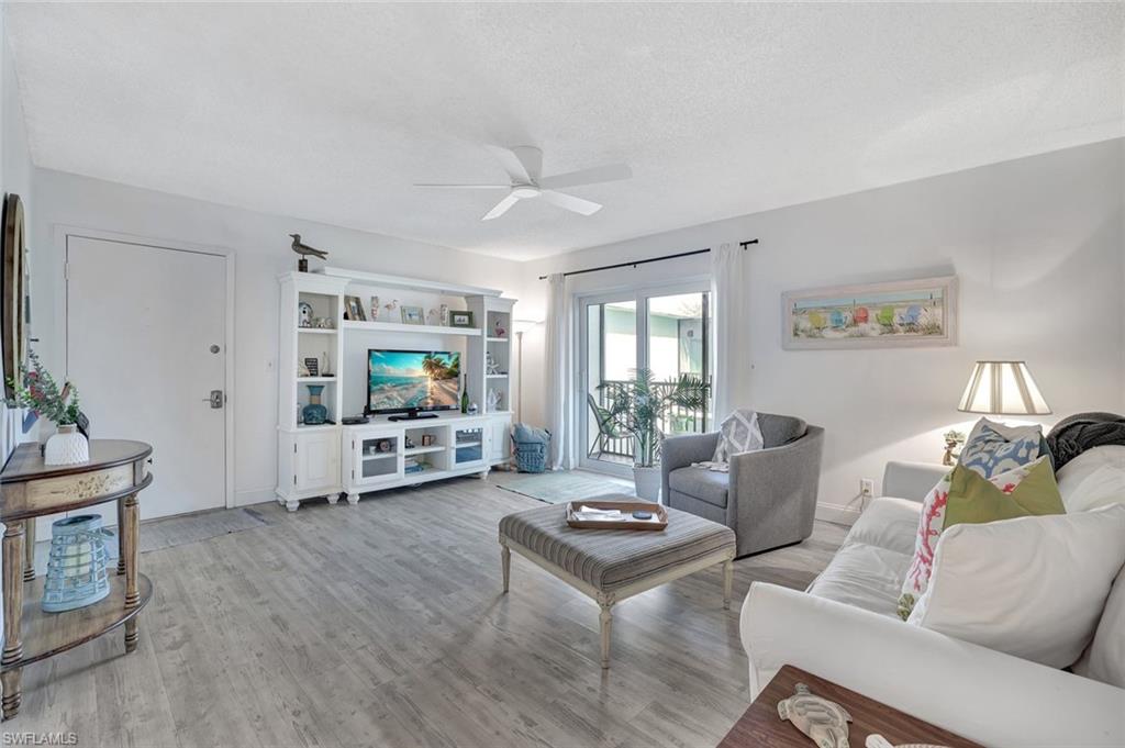 Living room featuring a textured ceiling, light hardwood / wood-style floors, and ceiling fan