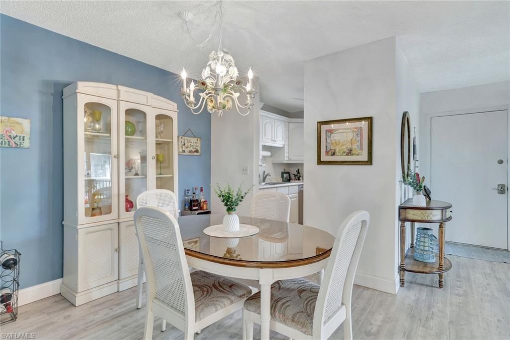 Dining space featuring an inviting chandelier, a textured ceiling, sink, and light hardwood / wood-style flooring