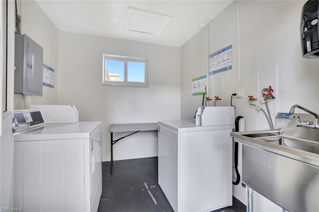 Clothes washing area featuring electric panel, sink, and washer and dryer