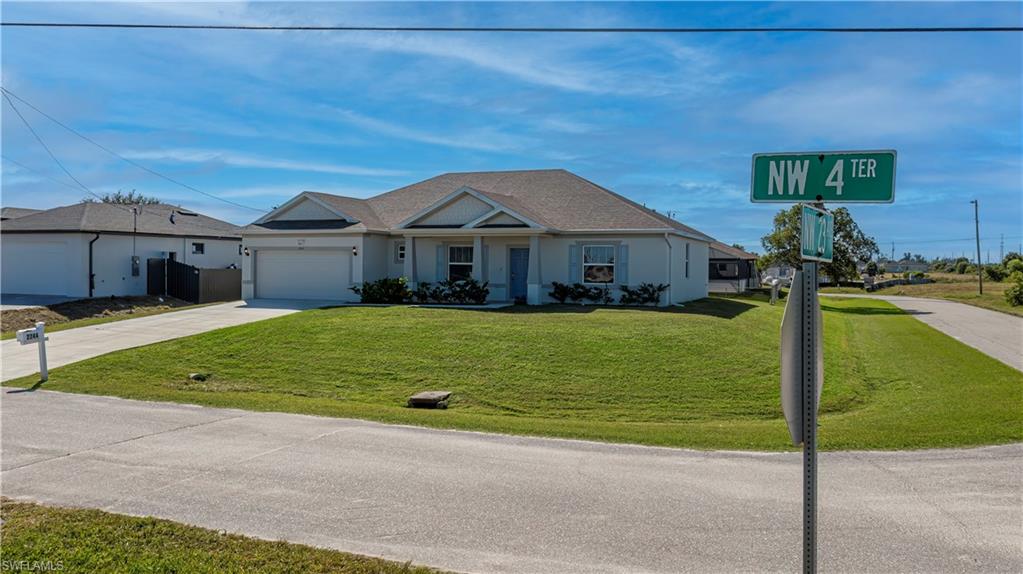 Single story home featuring driveway, a front yard, and an attached garage