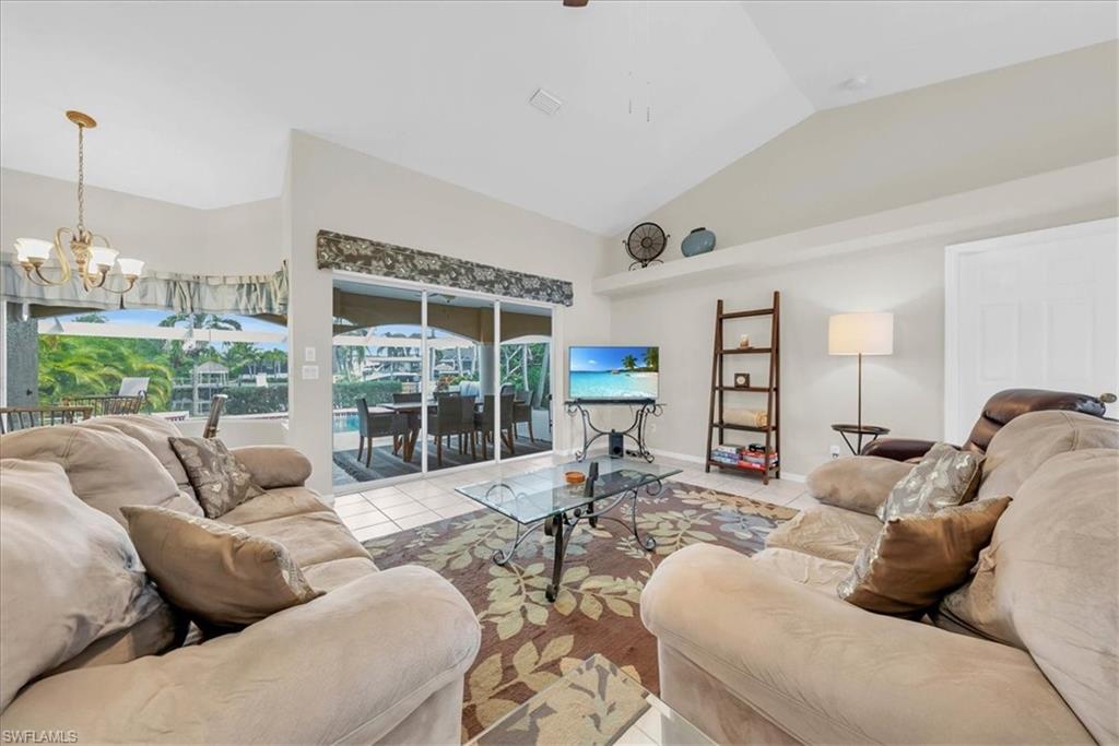 Living area featuring tile patterned floors, a sunroom, a chandelier, and high vaulted ceiling