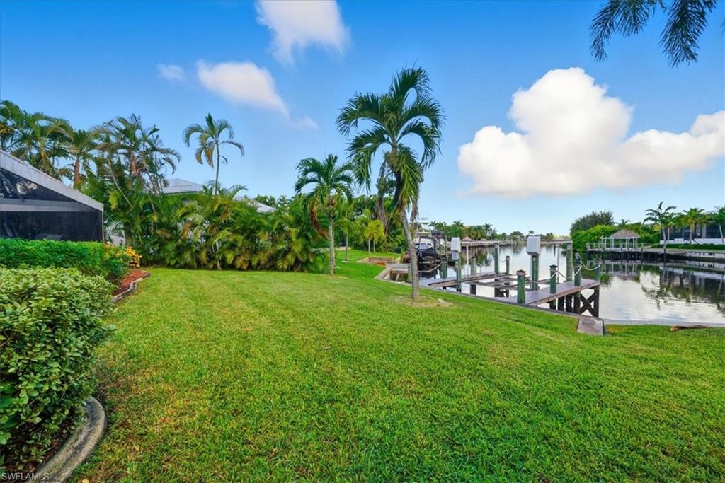 Dock area with boat lift, a water view, and a lawn