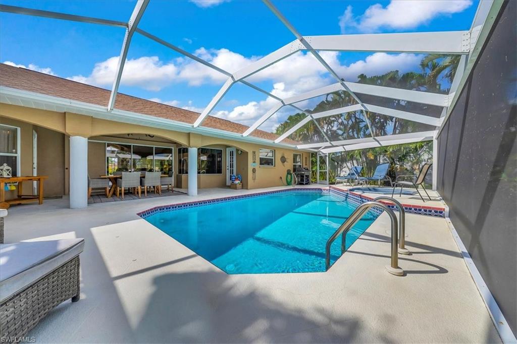 View of pool with a sunroom, a patio, glass enclosure, outdoor dining area, and a pool with connected hot tub