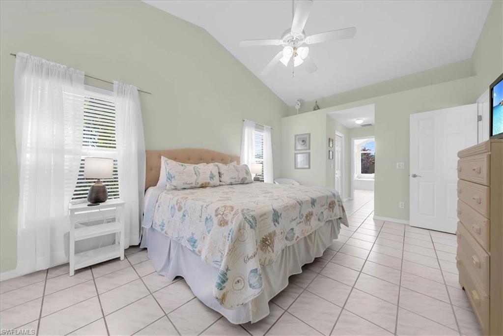 Bedroom with light tile patterned floors, multiple windows, ceiling fan, and high vaulted ceiling