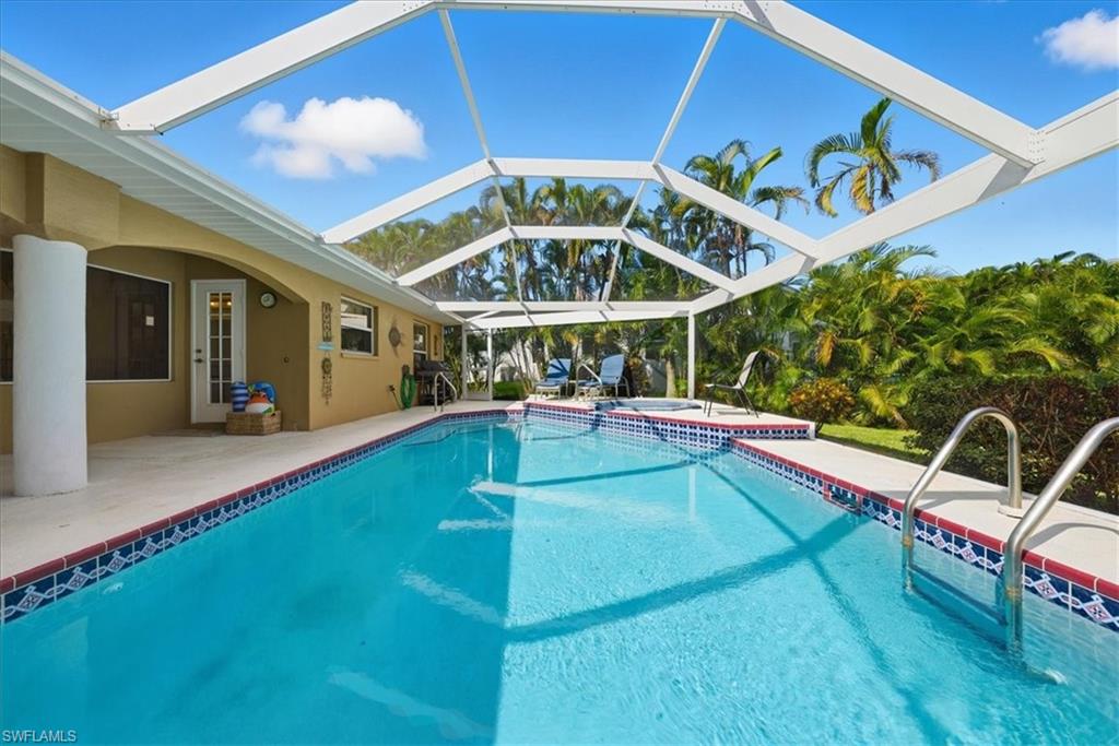 Outdoor pool featuring a patio area, an in-ground hot tub, glass enclosure, and a sunroom