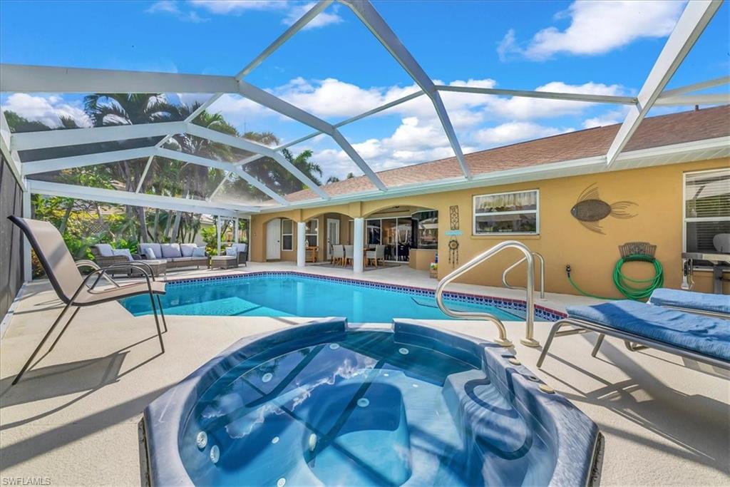 View of pool featuring a patio area, a sunroom, outdoor lounge area, a pool with connected hot tub, and a ceiling fan