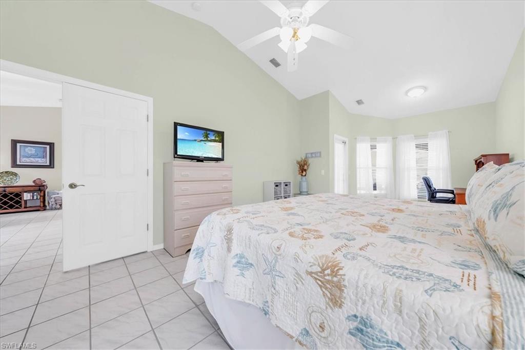 Bedroom featuring light tile patterned flooring, ceiling fan, and high vaulted ceiling