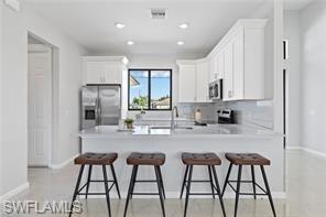 Kitchen with white cabinetry, light countertops, a breakfast bar, a peninsula, and recessed lighting