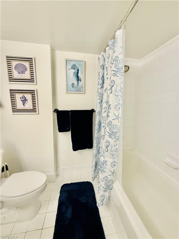 Bathroom featuring shower / bathtub combination with curtain and tile patterned floors