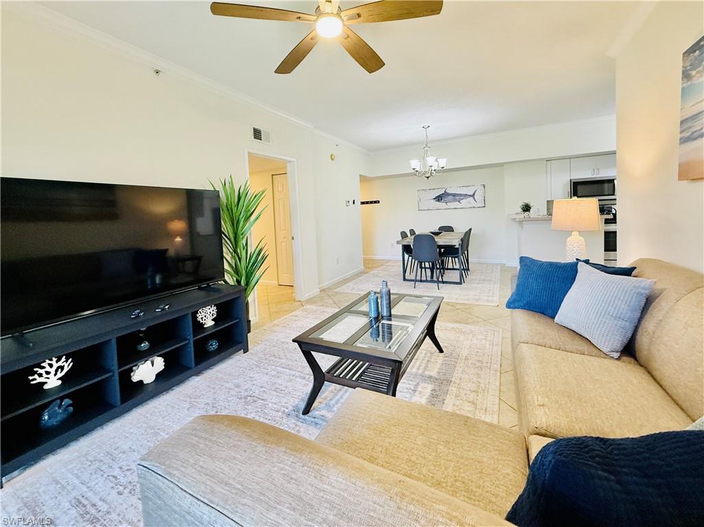 Living room with crown molding, ceiling fan, a chandelier, and light tile patterned floors