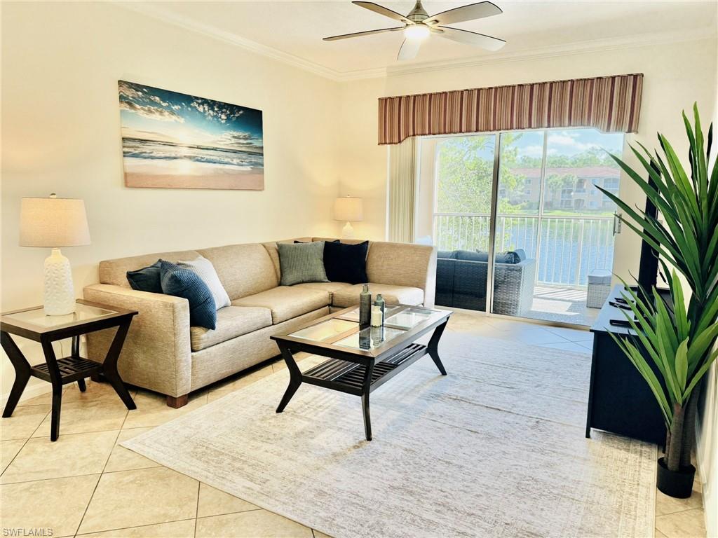 Living area featuring light tile patterned floors, ornamental molding, a water view, and a ceiling fan