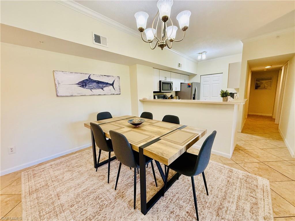 Dining room with light tile patterned floors, crown molding, and a chandelier
