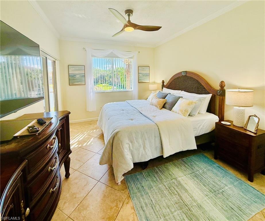 Bedroom featuring ornamental molding, light tile patterned flooring, and a ceiling fan