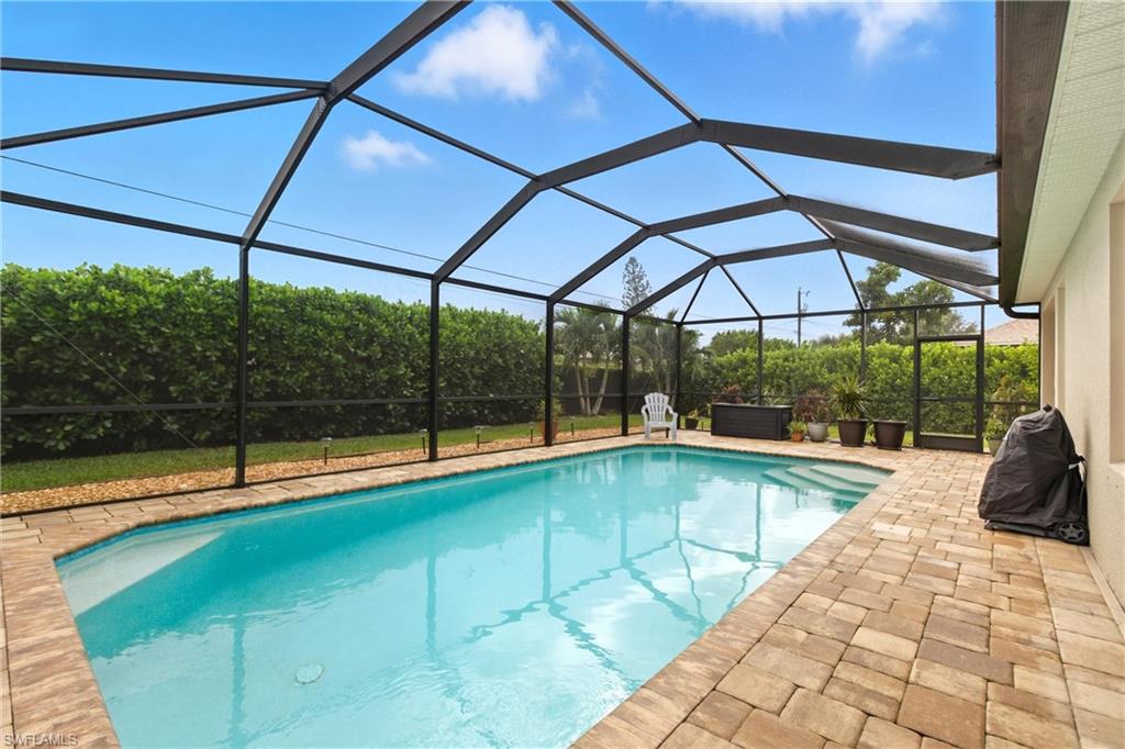 Swimming pool with screen enclosure, a sunroom, grilling area, and a patio area