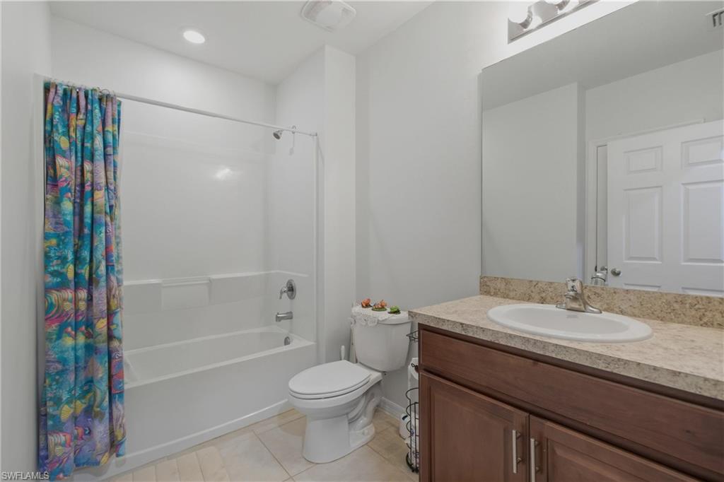 Bathroom featuring vanity, shower / bath combo with shower curtain, and light tile patterned flooring