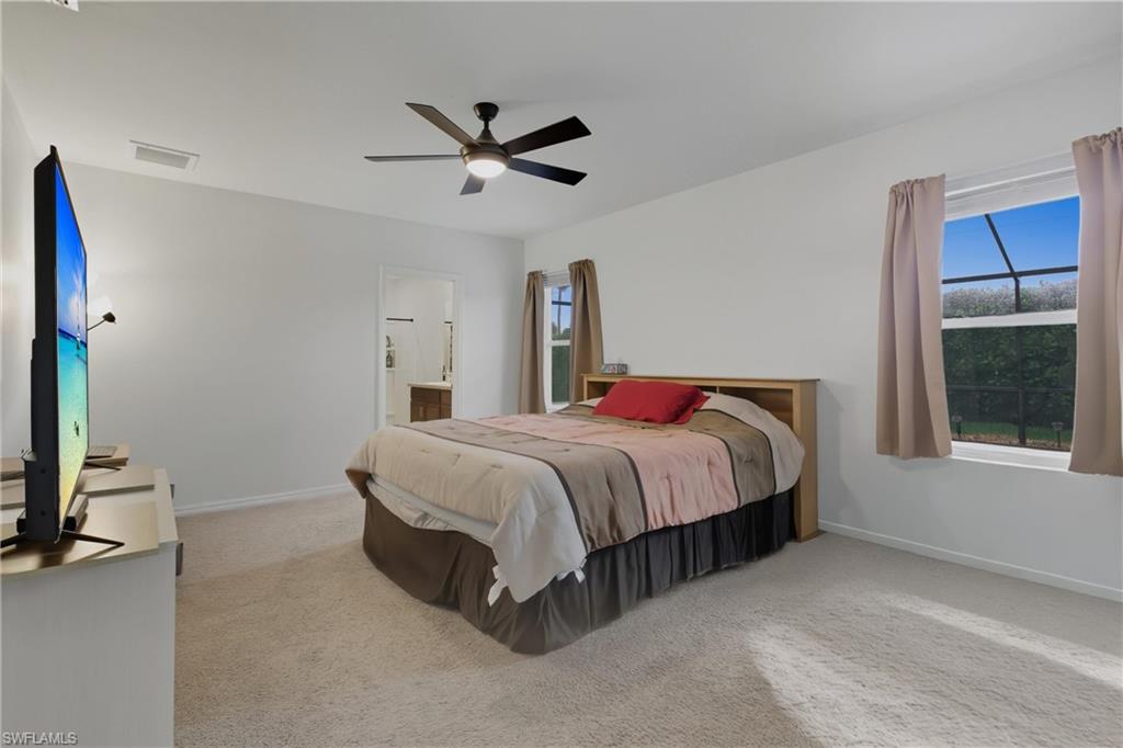 Bedroom featuring light colored carpet, a ceiling fan, and ensuite bathroom