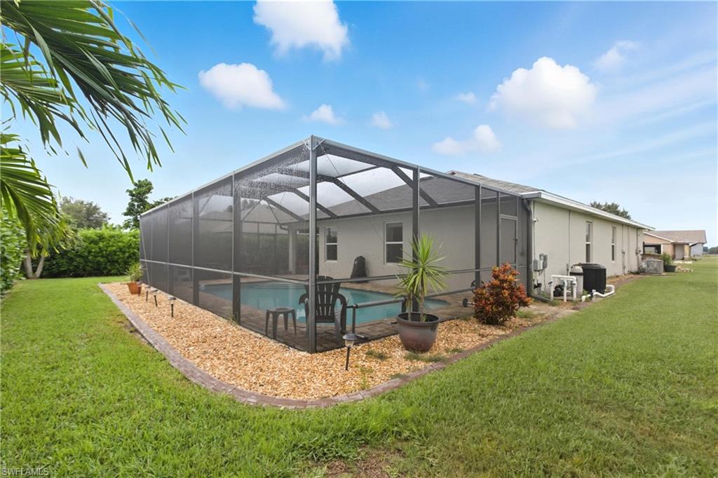 Back of house with a sunroom, a lawn, glass enclosure, an outdoor pool, and a patio area