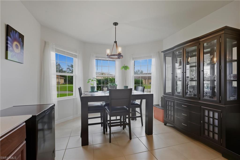 Dining area with light tile patterned floors, healthy amount of natural light, and a chandelier