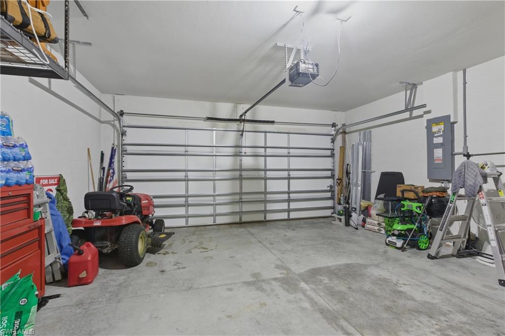 Garage featuring concrete block wall, electric panel, and a garage door opener