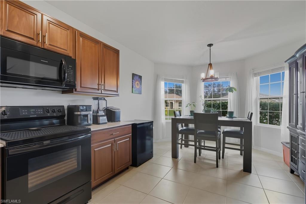 Kitchen featuring black appliances, light tile patterned floors, pendant lighting, and plenty of natural light
