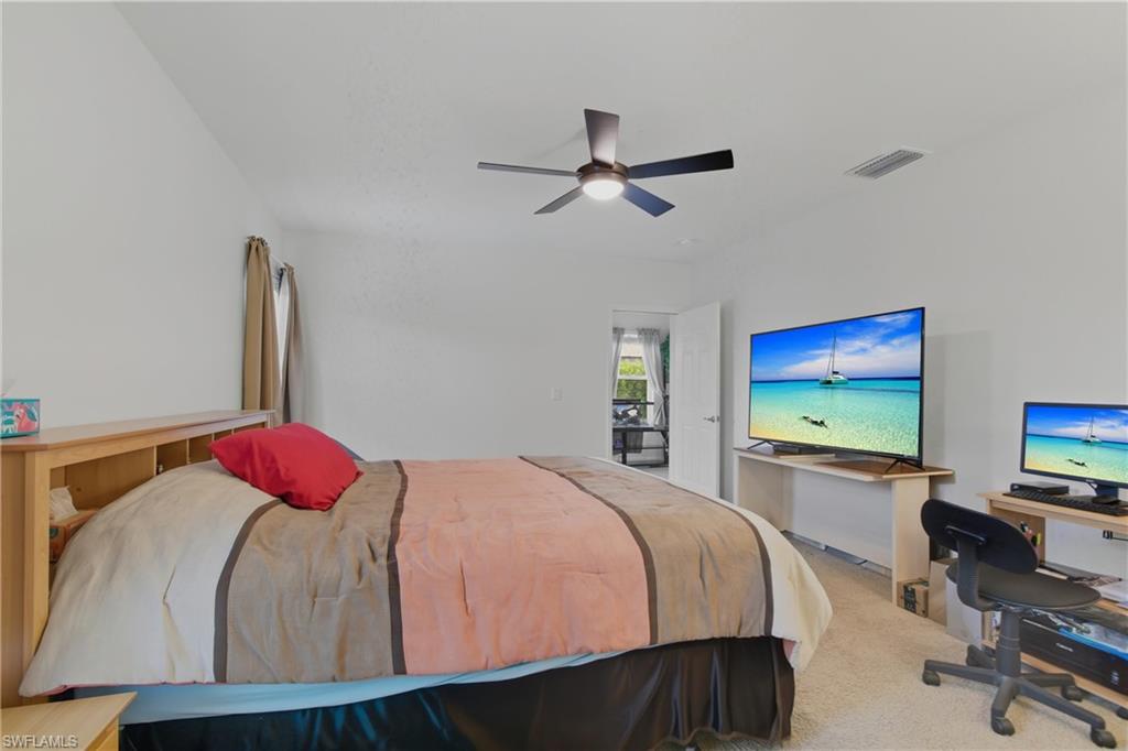 Carpeted bedroom with an office area and ceiling fan