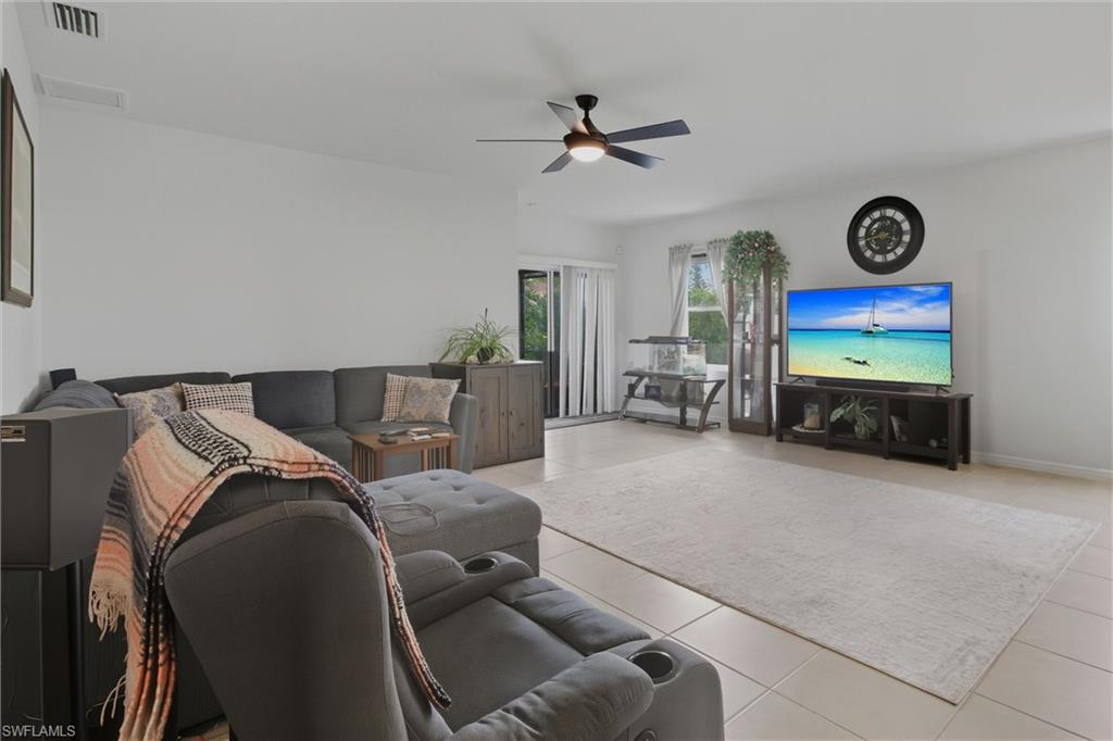 Tiled living area featuring a ceiling fan and baseboards