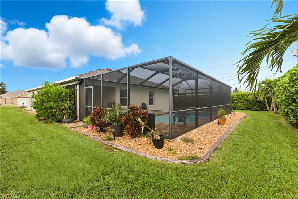 Rear view of property featuring screen enclosure, an outdoor pool, a sunroom, and a lawn