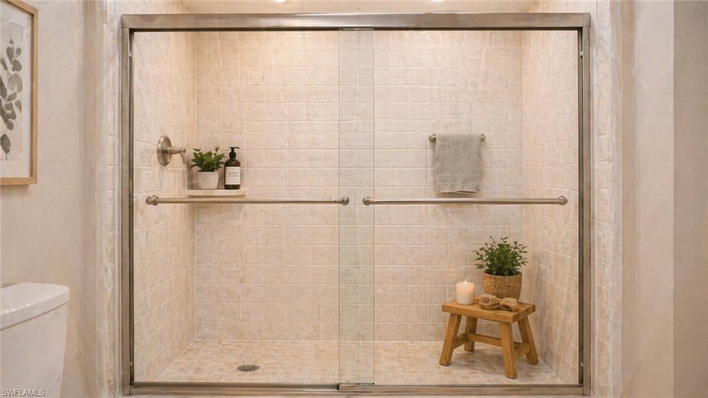 Glass-enclosed shower featuring light-toned tile walls, a coordinating tiled shower pan, a brushed nickel showerhead, and a matching towel bar