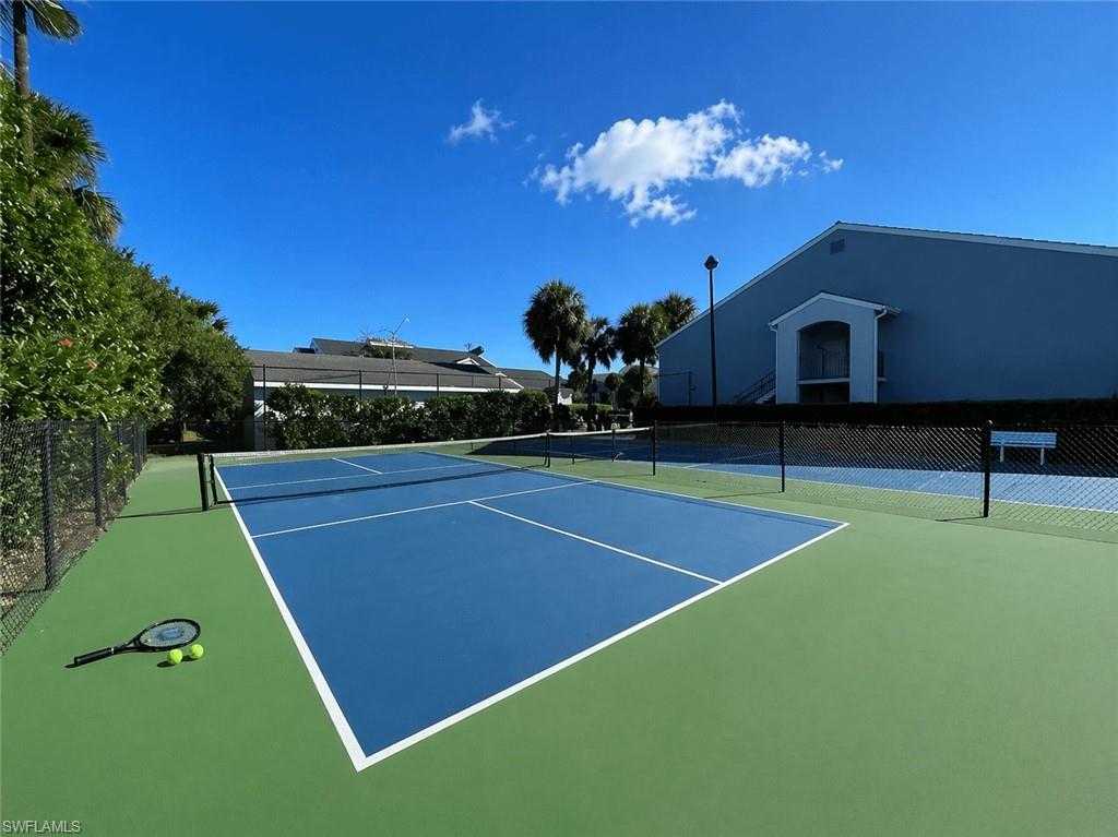 Tennis court with blue playing surface and green surrounds