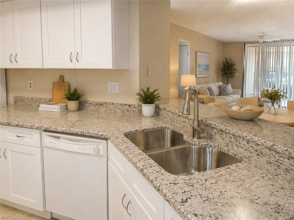 Kitchen featuring white shaker-style cabinetry, light granite countertops, and a double basin stainless steel sink with a gooseneck faucet