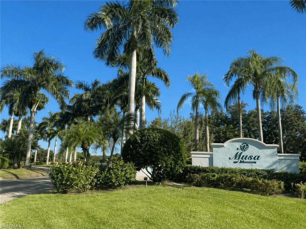 Community entry monument with decorative landscaping, mature palm trees, and manicured green spaces