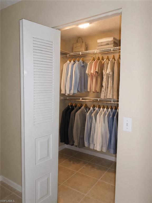 Walk-in closet featuring louvered bi-fold doors, recessed lighting, and tile flooring