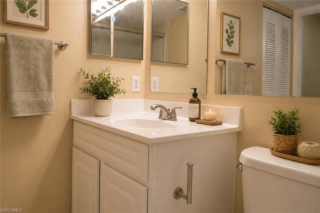 Bathroom vanity with an integrated sink, brushed nickel faucet, and a wall-mounted mirror