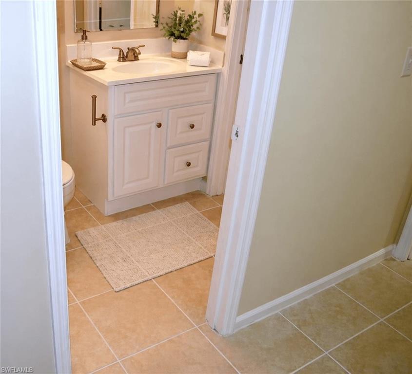 Bathroom featuring a white vanity with a single basin, light-toned countertop, and bronze-finish faucet