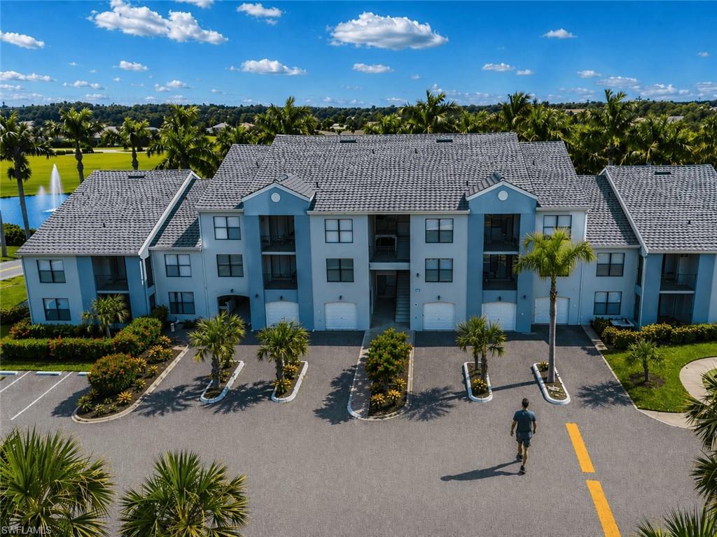 Multi-story residential building featuring a tile roof, individual garage doors, and private balconies