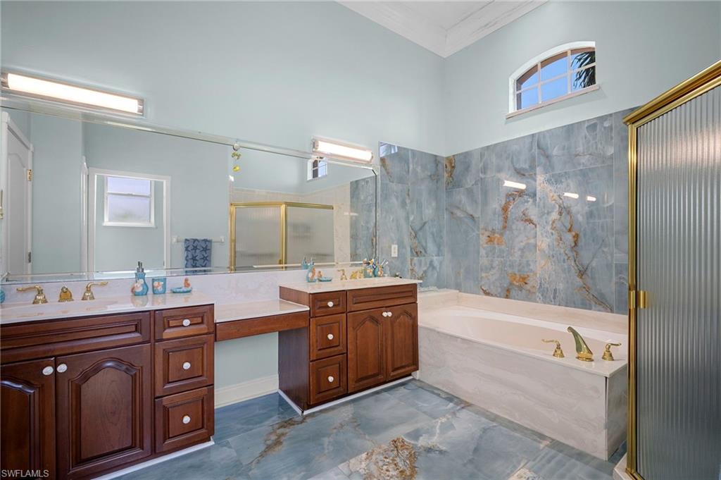 Full bathroom featuring a stall shower, a bath, double vanity, and crown molding
