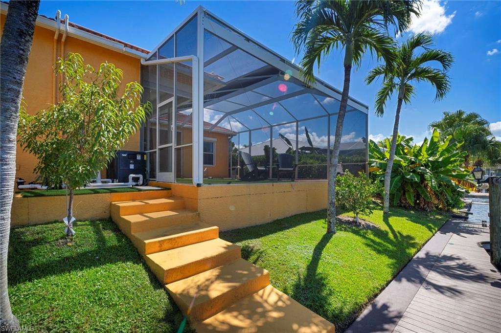 Back of house with a lanai, a sunroom, stucco siding, and a yard