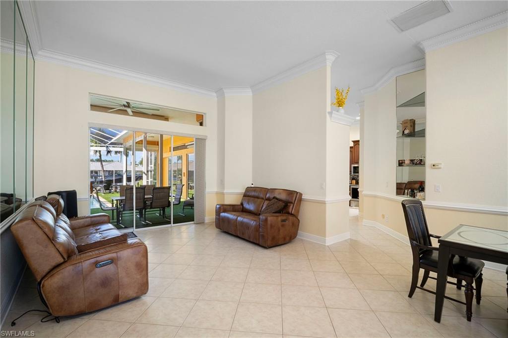 Living room featuring crown molding, a sunroom, tile patterned flooring, and ceiling fan