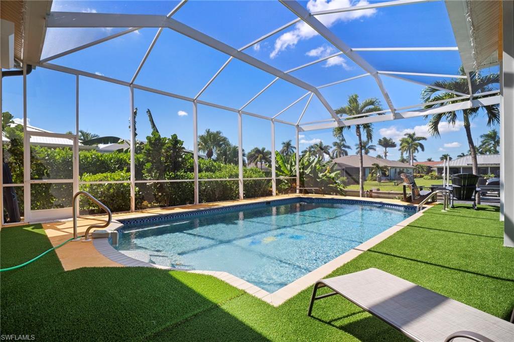 Swimming pool with a yard, glass enclosure, a sunroom, and a patio