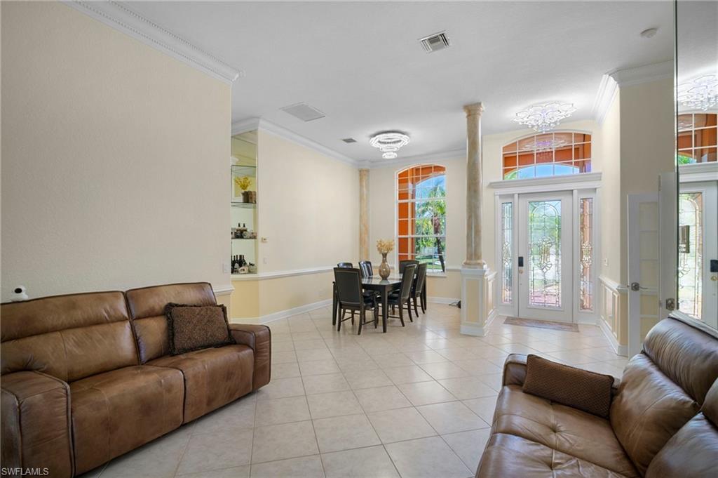 Living room with decorative columns, crown molding, and light tile patterned floors