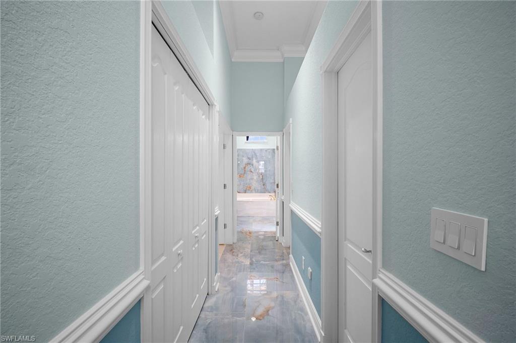 Hall with a textured wall and crown molding